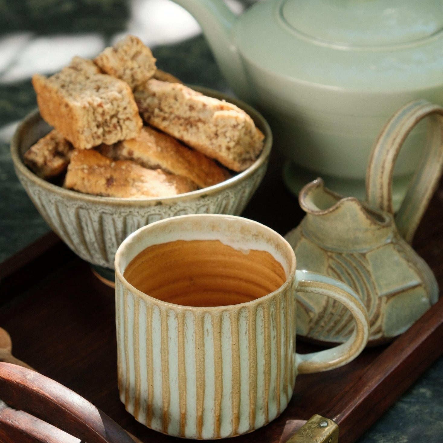 MANTRA LIVING fluted mug in desert oasis glaze on a wooden tray with a teapot, milk jug and a bowl of rusks.
