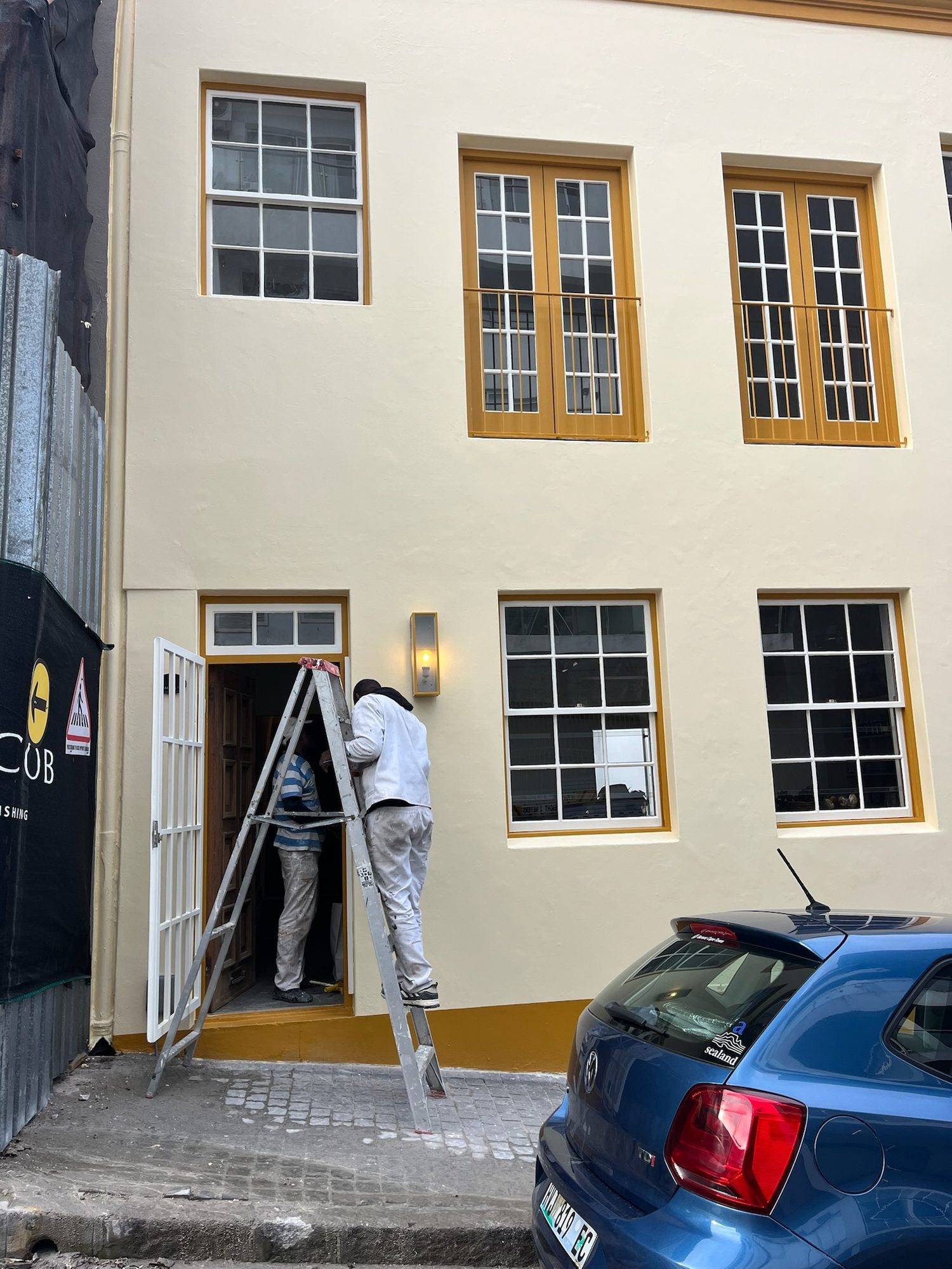 A painter on a ladder finishing the front of the building