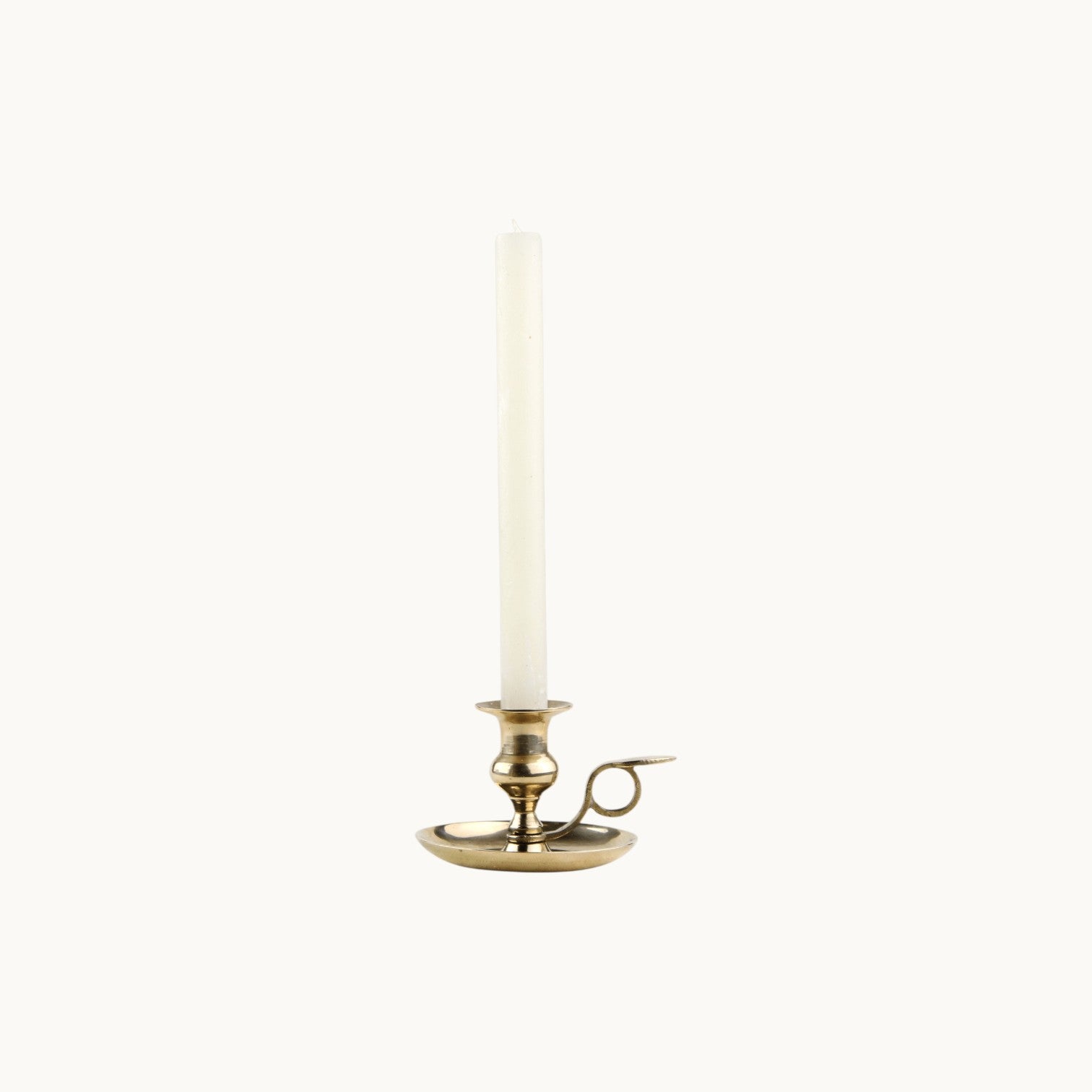 Mantra Living Frosted Dinner Candle in cream, standing in a small brass chamberstick holder. #Color_Cream
