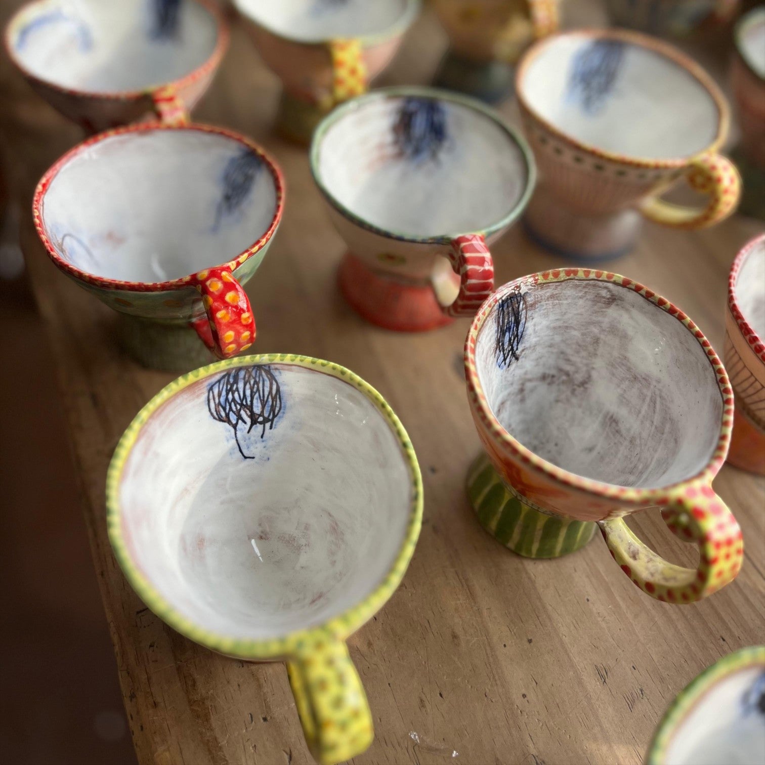 MANTRA LIVING Isabella tea cups with unique hand-painted pastel designs and patterned handles on a wooden surface