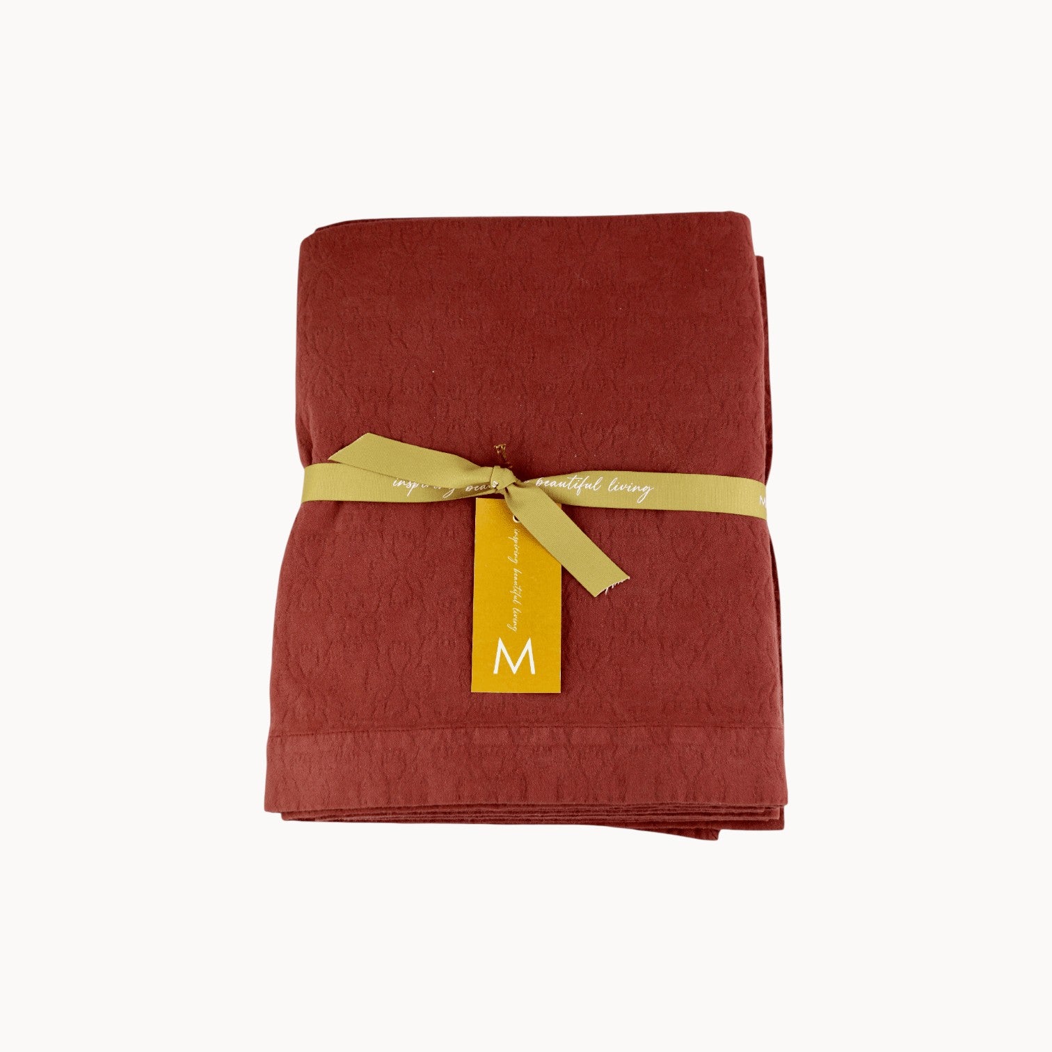 Mantra Living Hibiscus cotton tablecloth in maple red, folded and tied with an ochre ribbon and gift tag. #Color_Maple