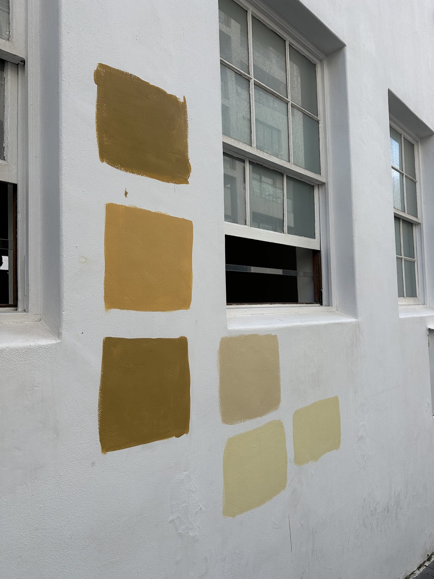 Six patches of ochre paint tested on the white facade