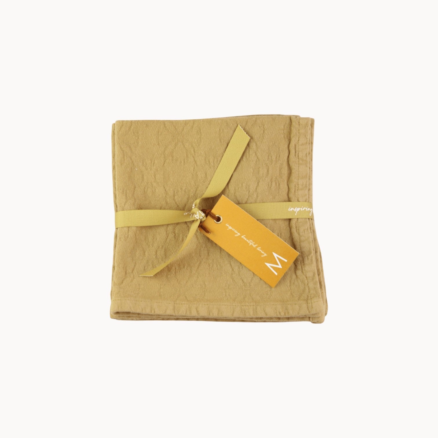 Mantra Living Hibiscus cotton napkins in butterscotch, set of four folded jacquard-woven napkins tied with a branded ribbon and tag. #Color_Butterscotch