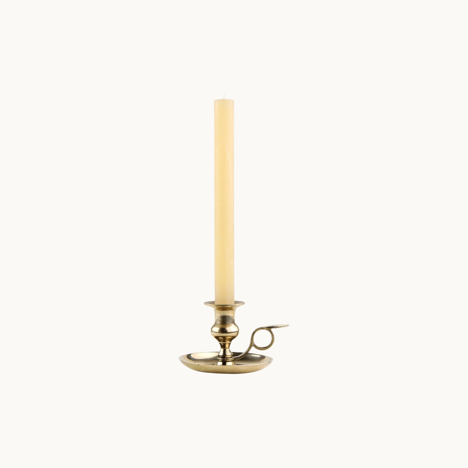 Mantra Living Frosted Dinner Candle in honey, a warm ivory taper in a brass chamberstick holder. #Color_Honey