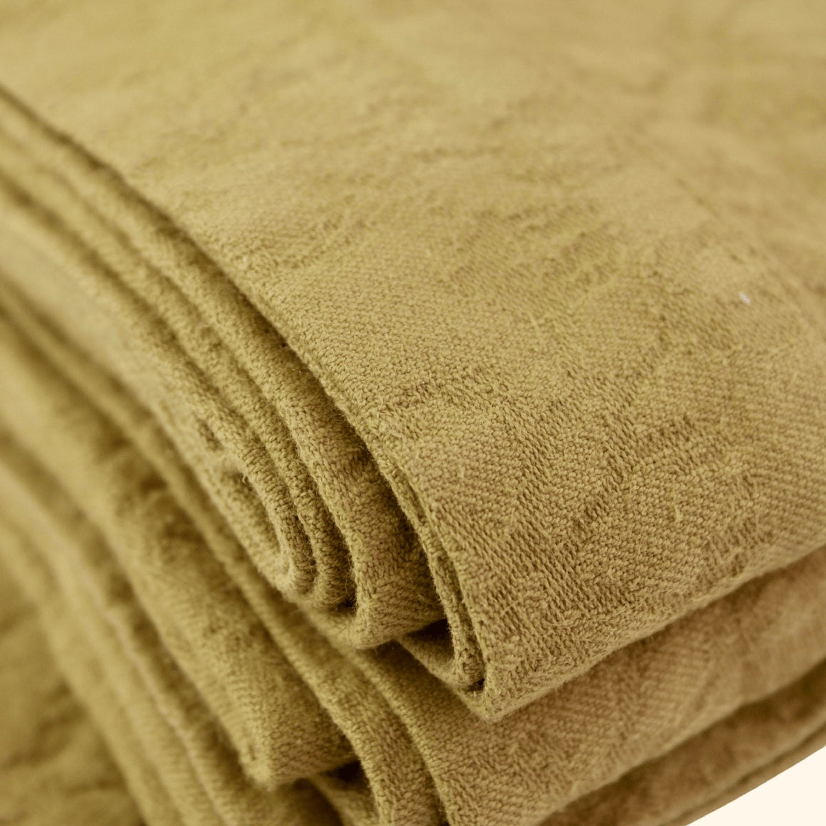 Mantra Living Hibiscus cotton tablecloth in butterscotch, close view of the folded jacquard weave and hemmed border. #Color_Butterscotch