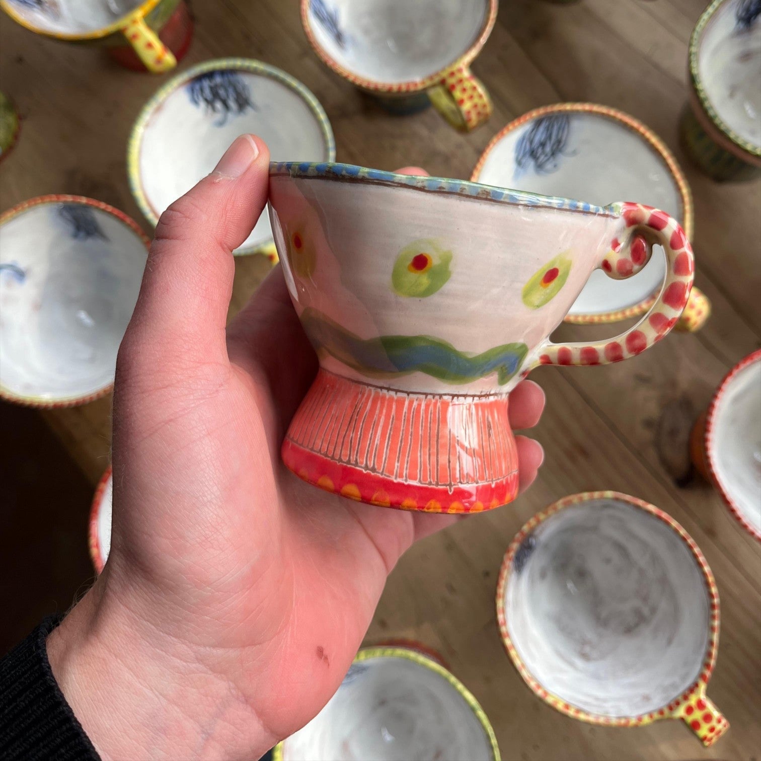 MANTRA LIVING Isabella tea cup held in hand, featuring unique hand-painted pastel patterns on ceramic.