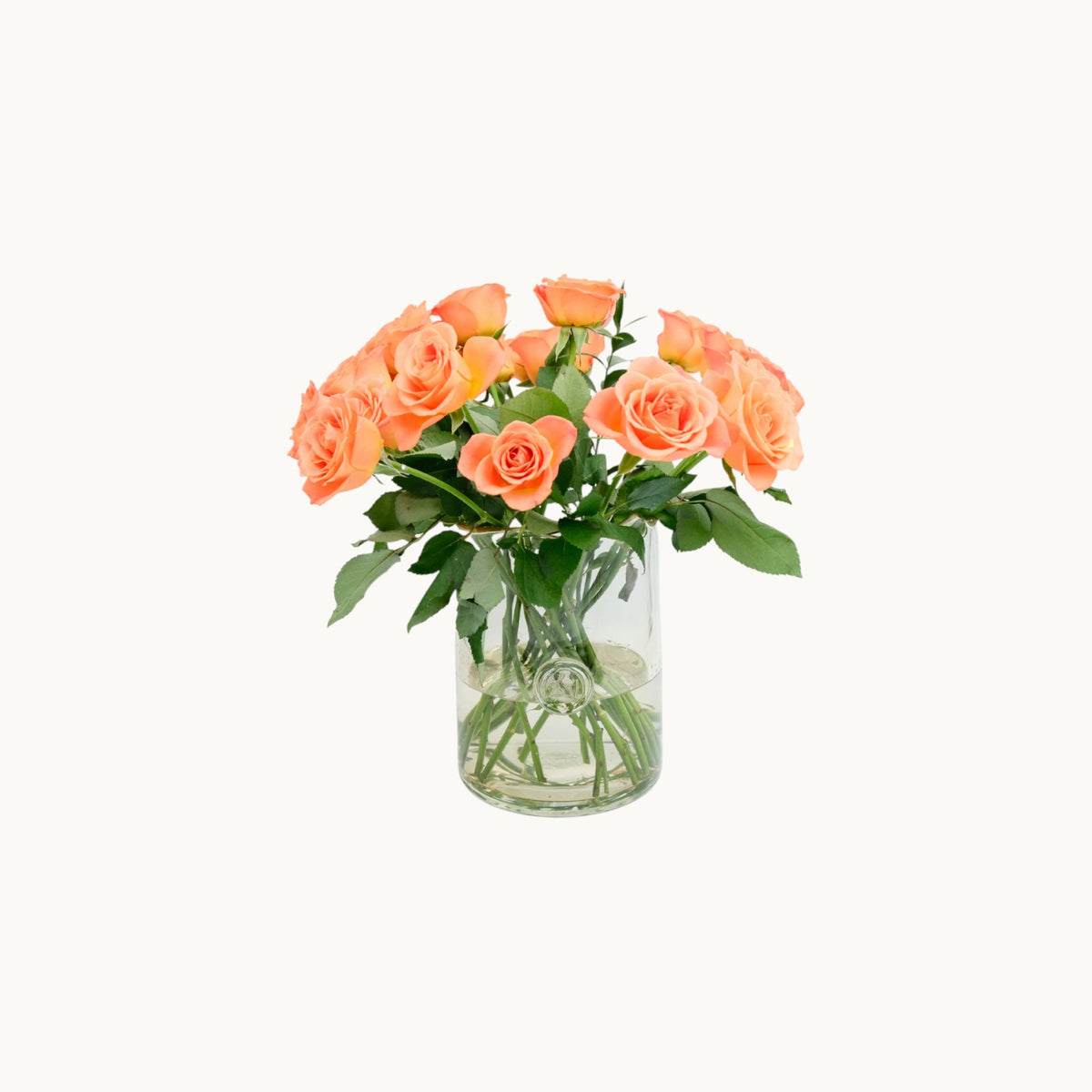MANTRA LIVING Lara Vase in clear glass filled with a bouquet of fresh peach-coloured roses on a white background.