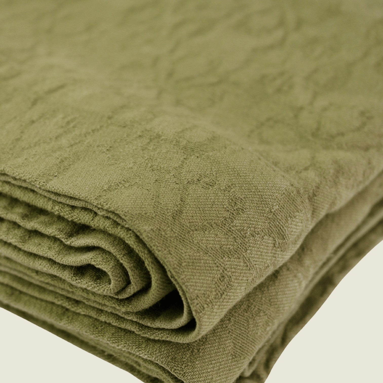 Mantra Living Hibiscus cotton tablecloth in pistachio green, close view of the folded jacquard weave and hemmed border. #Color_Pistachio