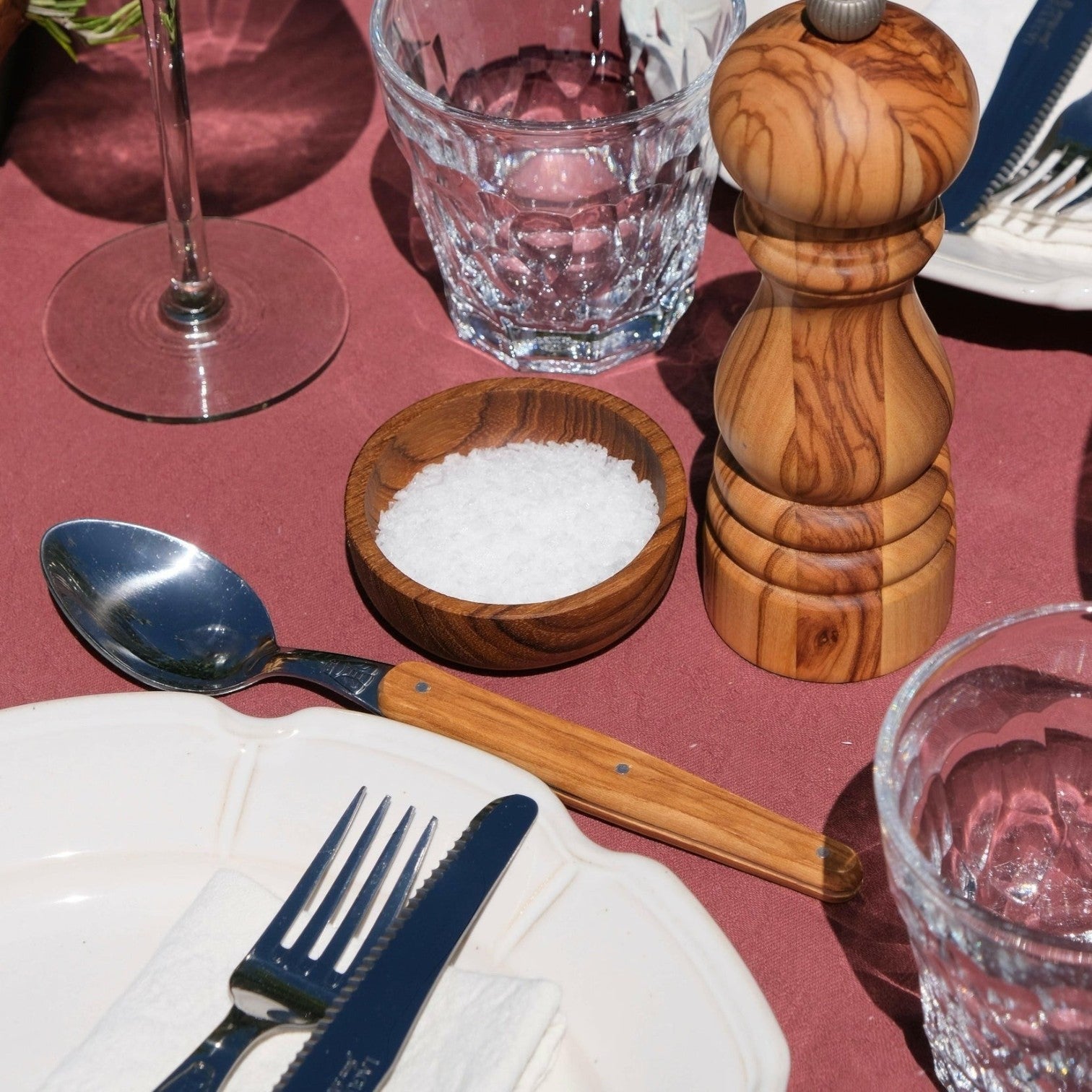 Mantra Living teak salt pinch pot in the large size, filled with sea salt flakes beside a wooden pepper mill on a table setting. #Size_Large